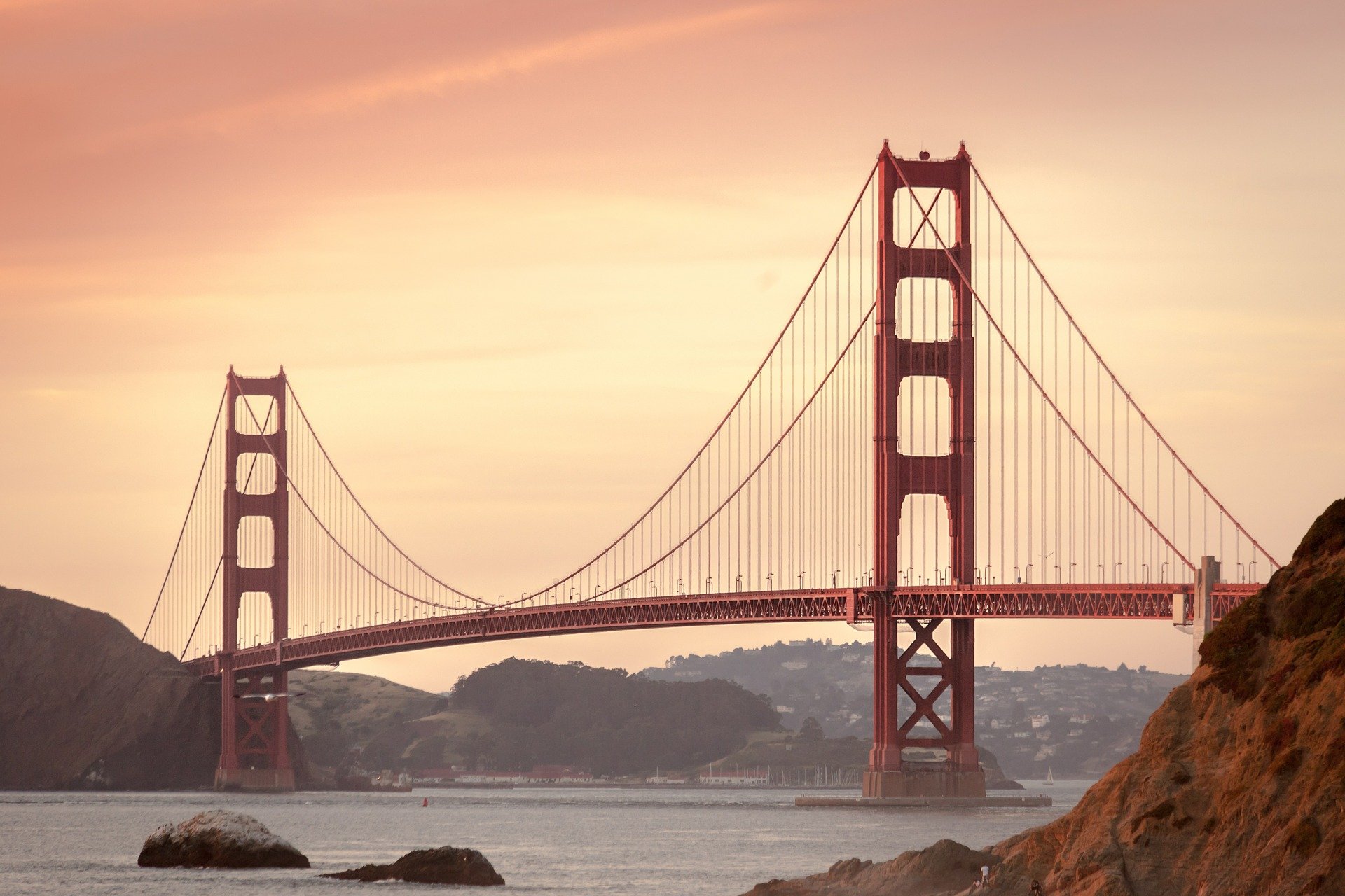 Golden Gate Bridge over water with a pink sky