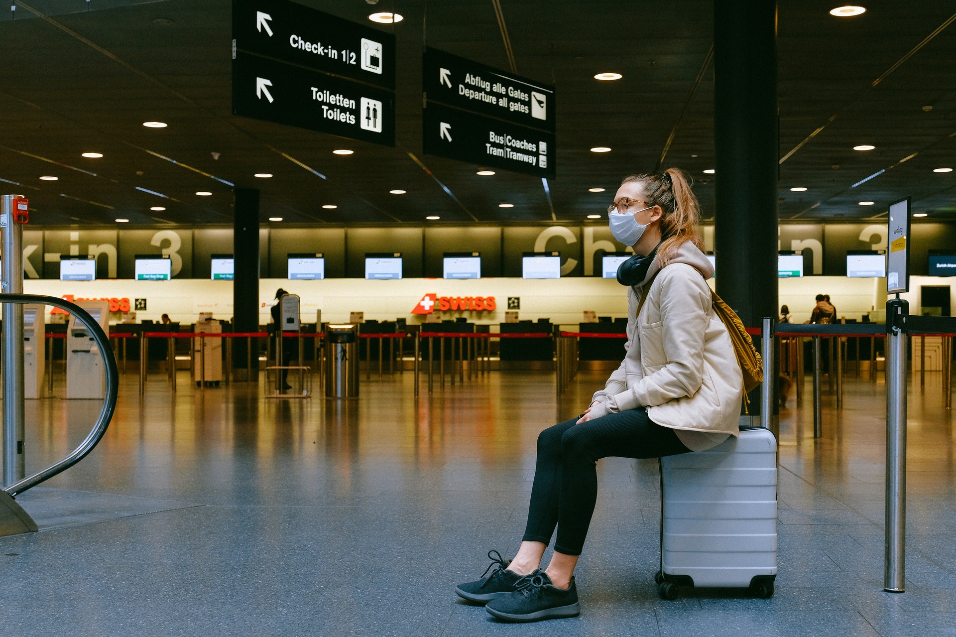 a woman sitting on a luggage in an airport