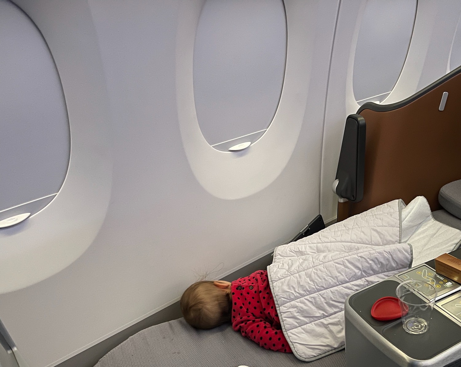 a baby sleeping on a bed in an airplane