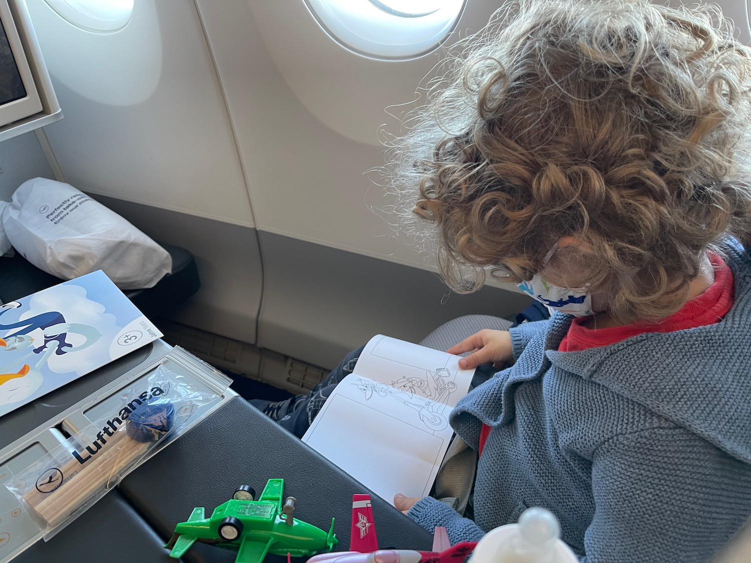 a child sitting in an airplane with a mask on