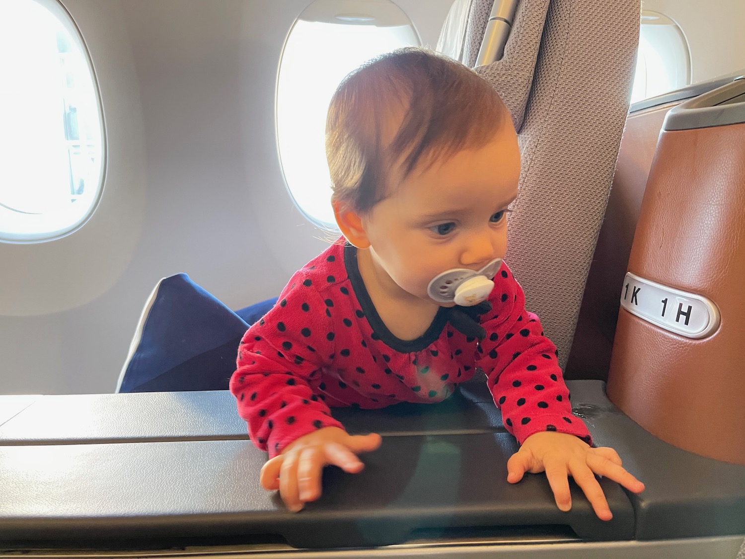 a baby in a red dotted outfit on an airplane