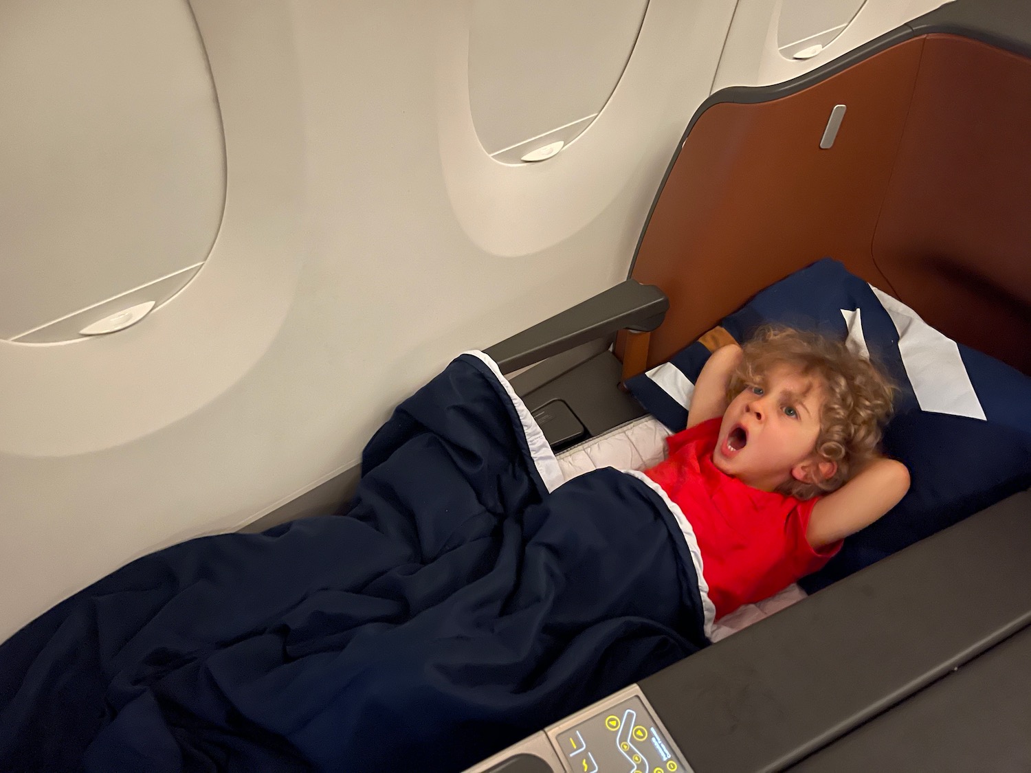a child lying on a bed in an airplane