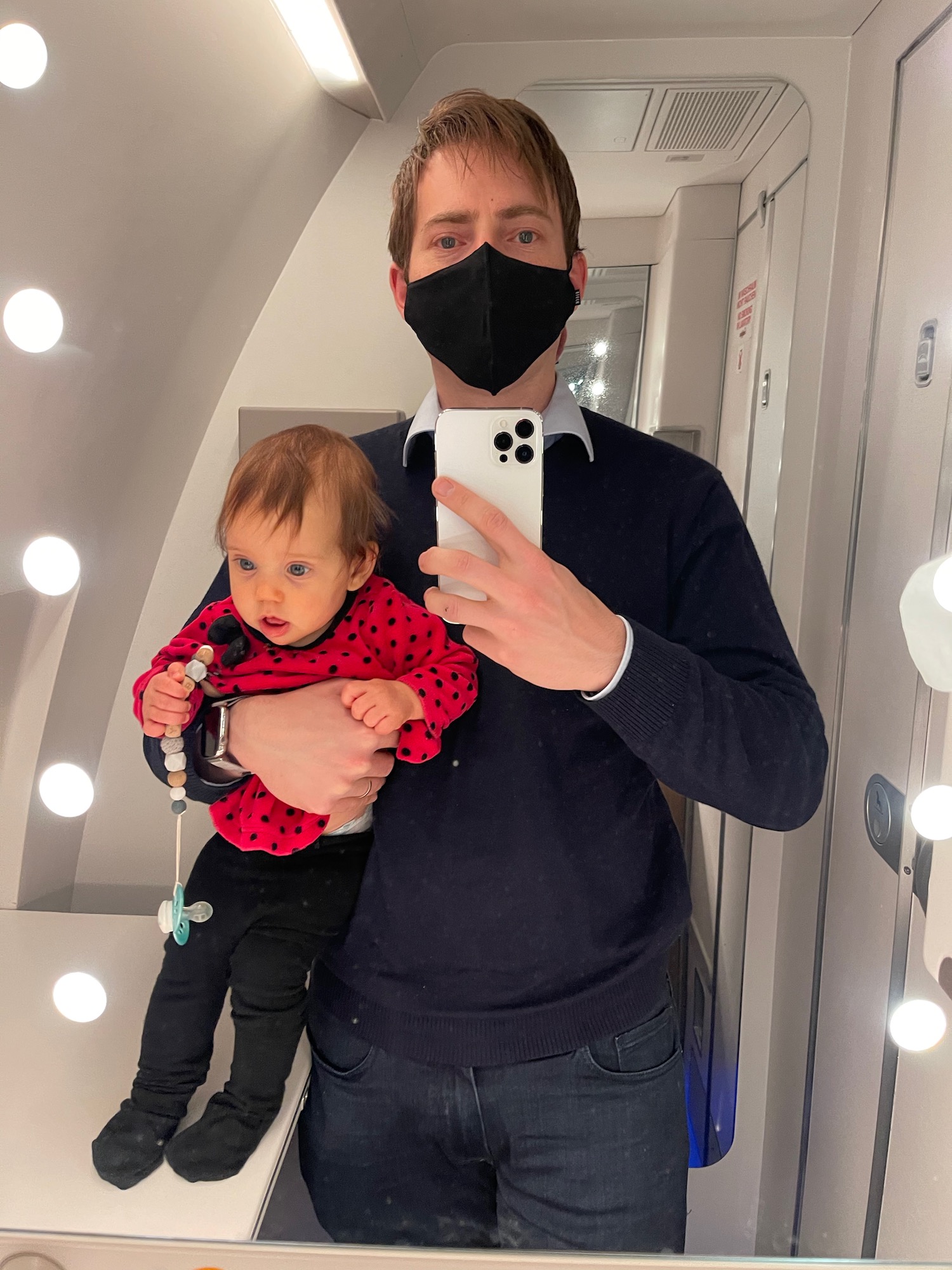 a man holding a baby wearing a black face mask