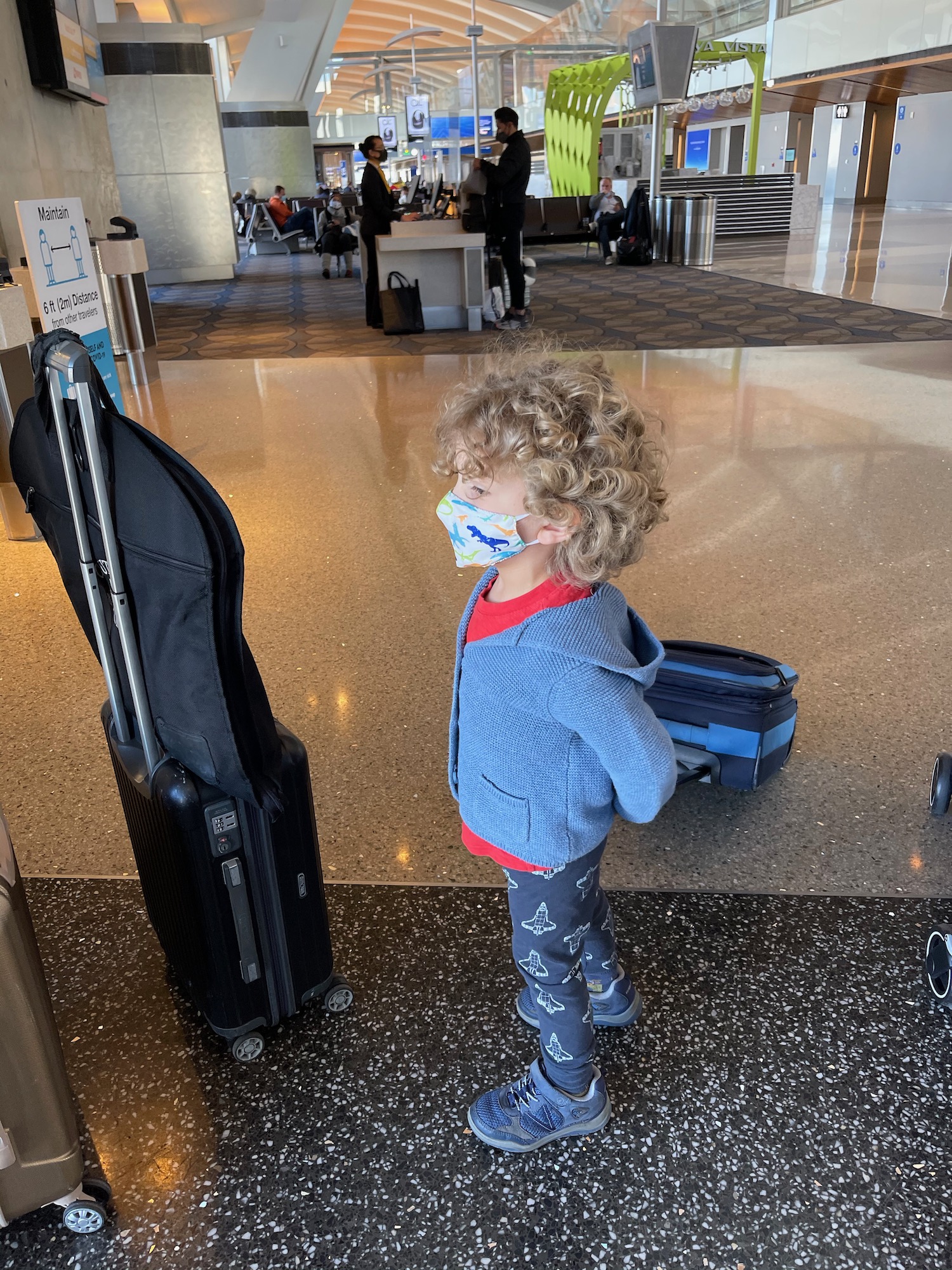 a child wearing a mask standing next to luggage