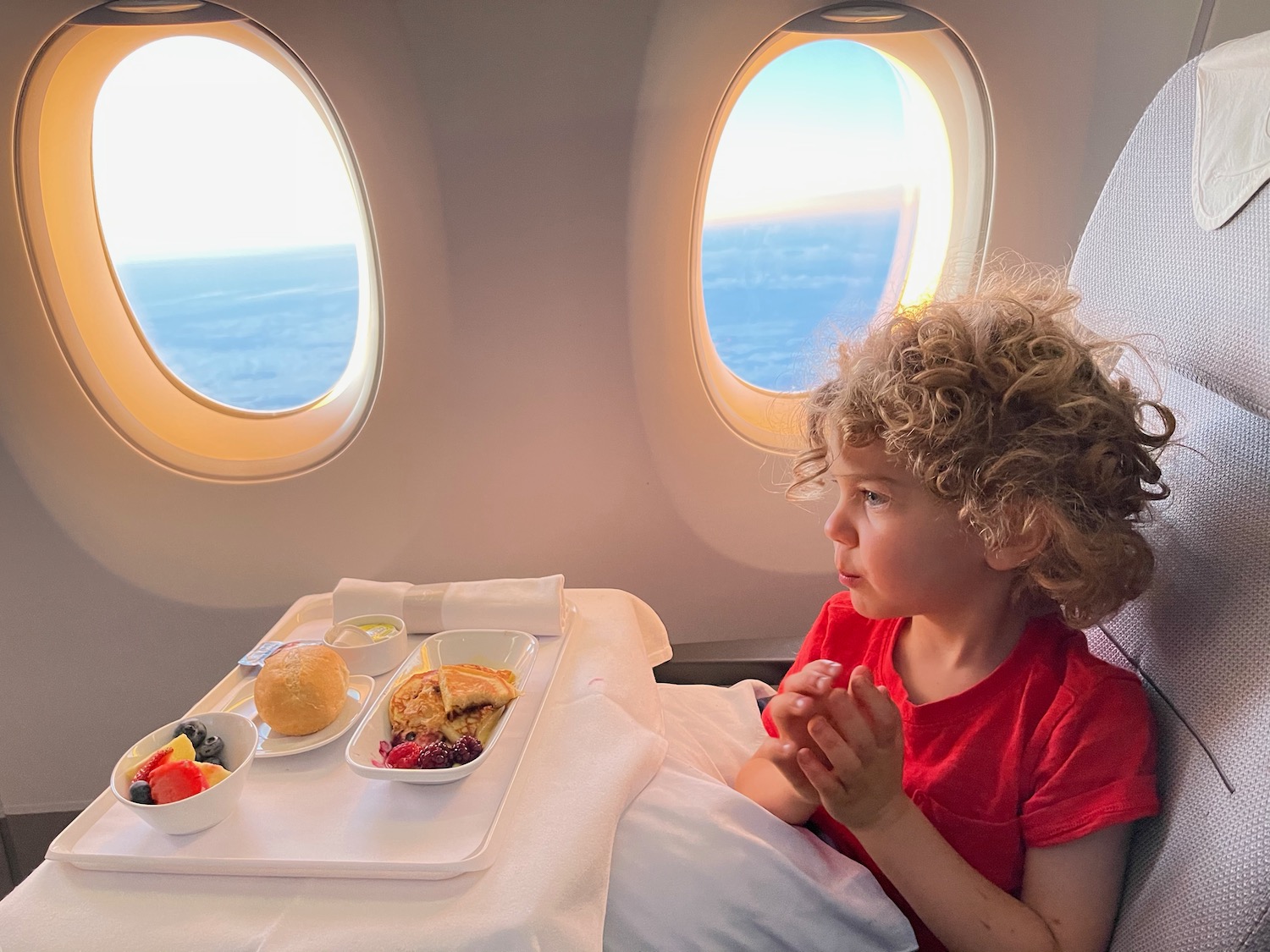 a child in a bed with food on a tray