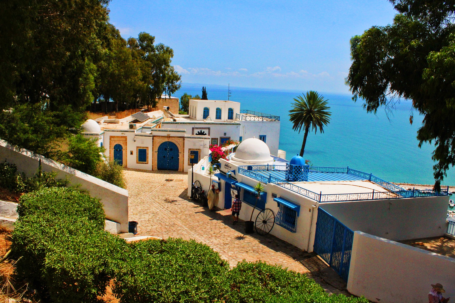 a white building with blue doors and a blue gate next to a body of water