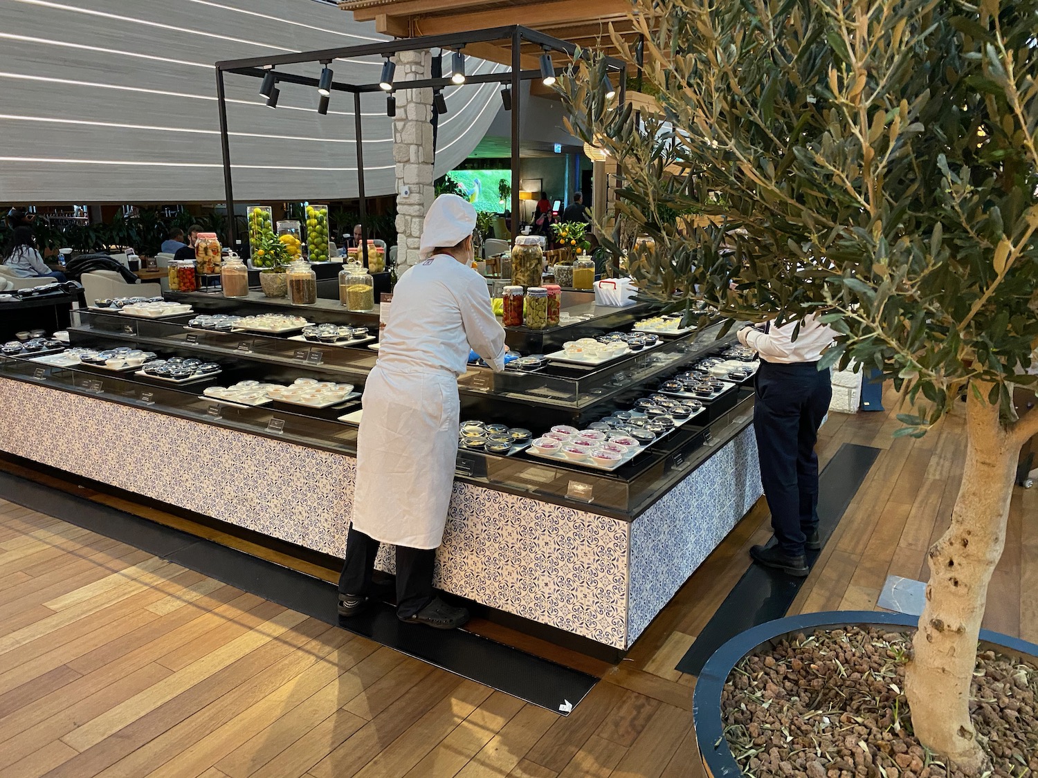 a woman in a white coat standing in front of a counter with food