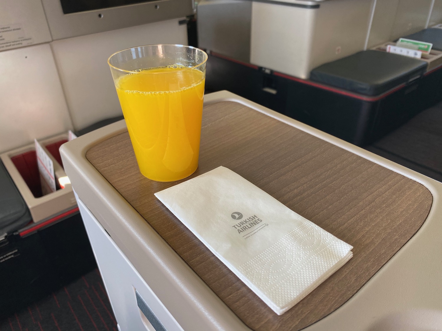 a glass of orange juice and napkin on a table