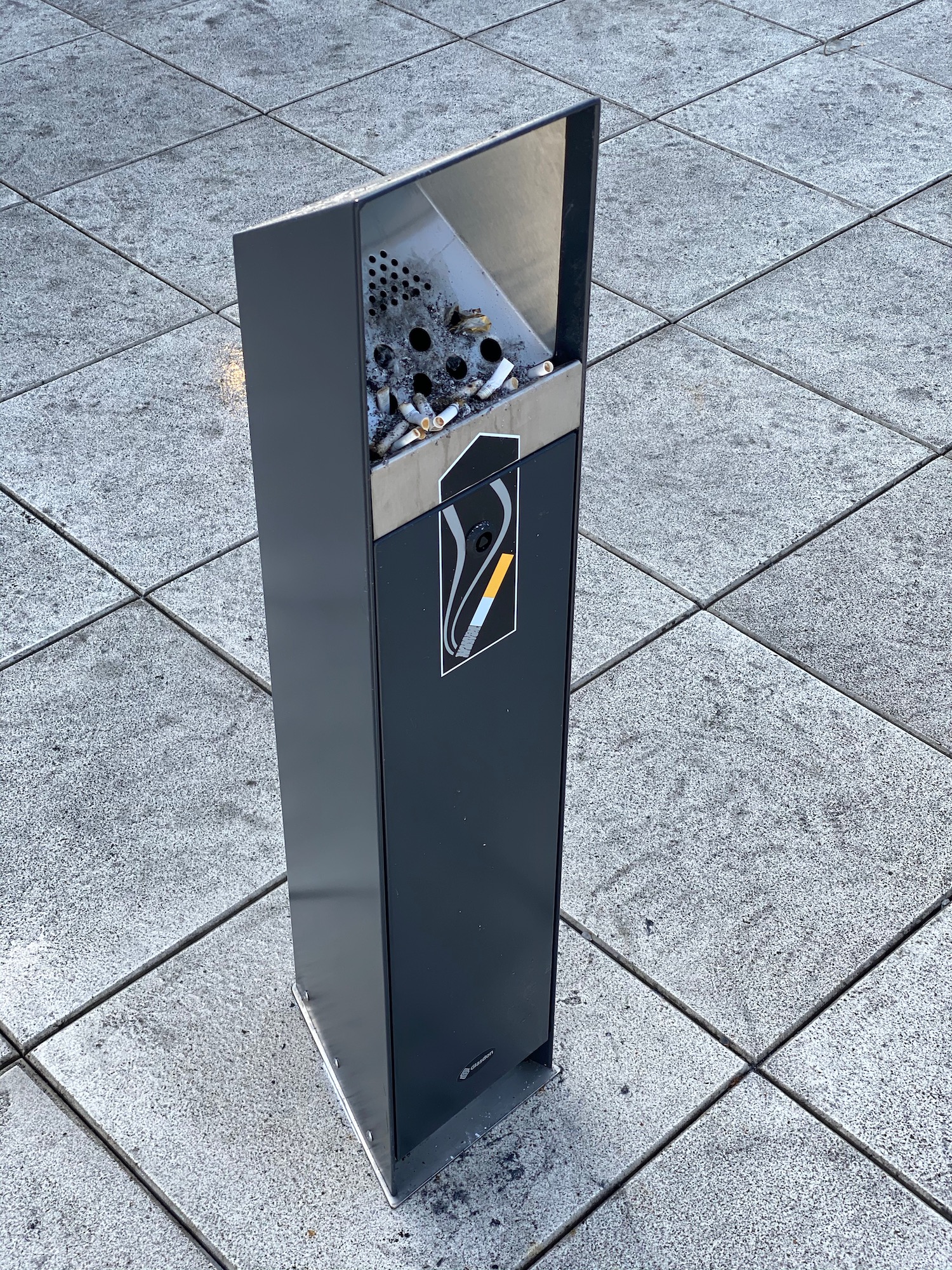 a cigarette dispenser on a tile floor