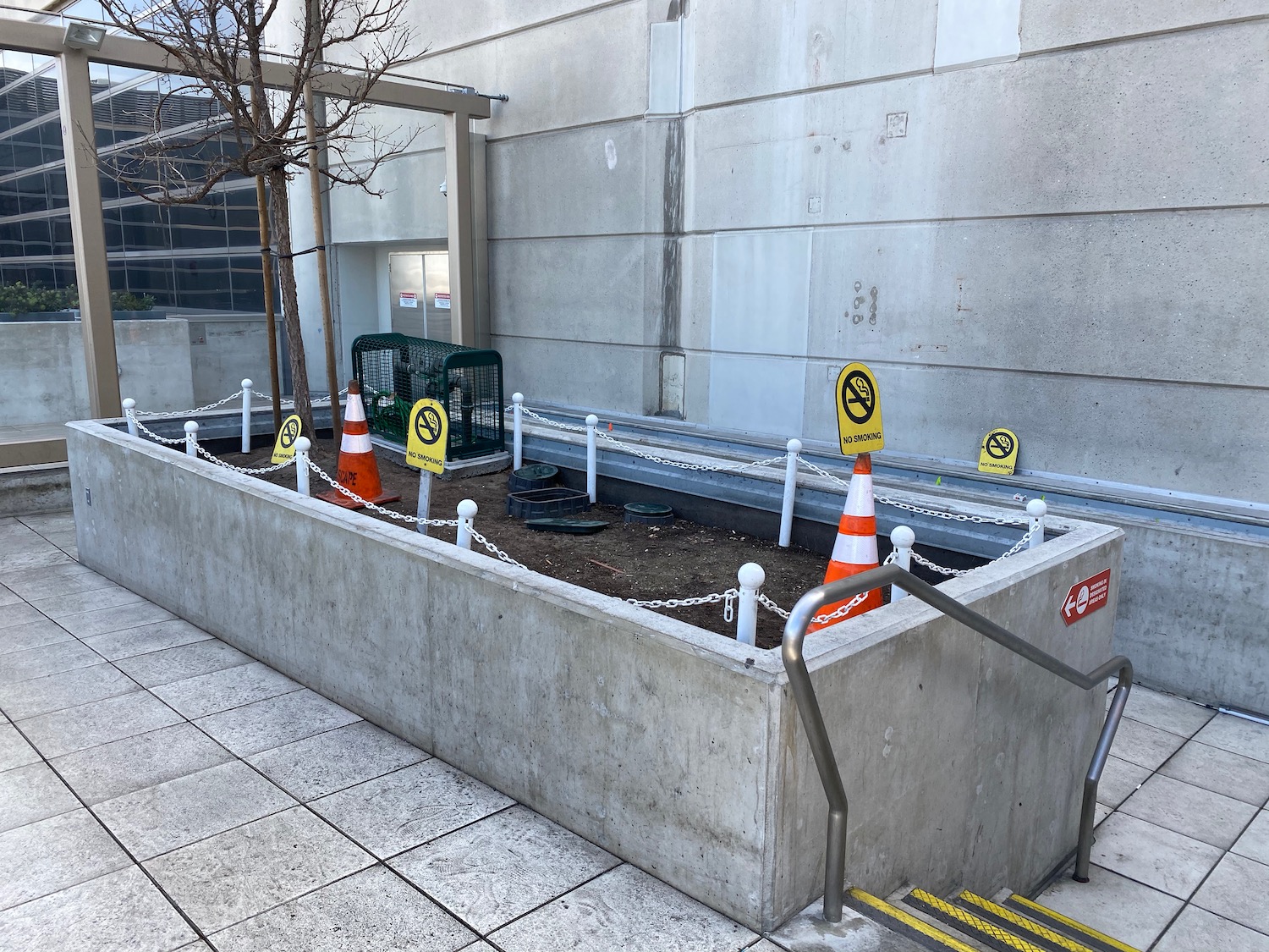 a concrete planter with orange and white cones and a metal railing