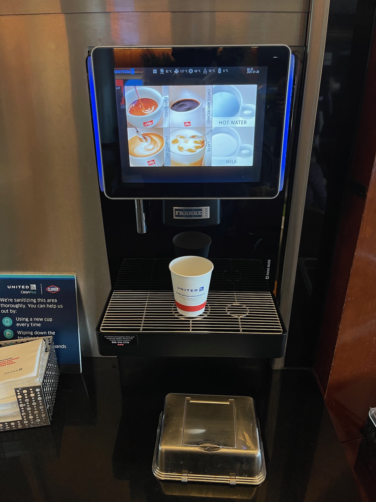 a coffee machine with a screen and a cup on the shelf