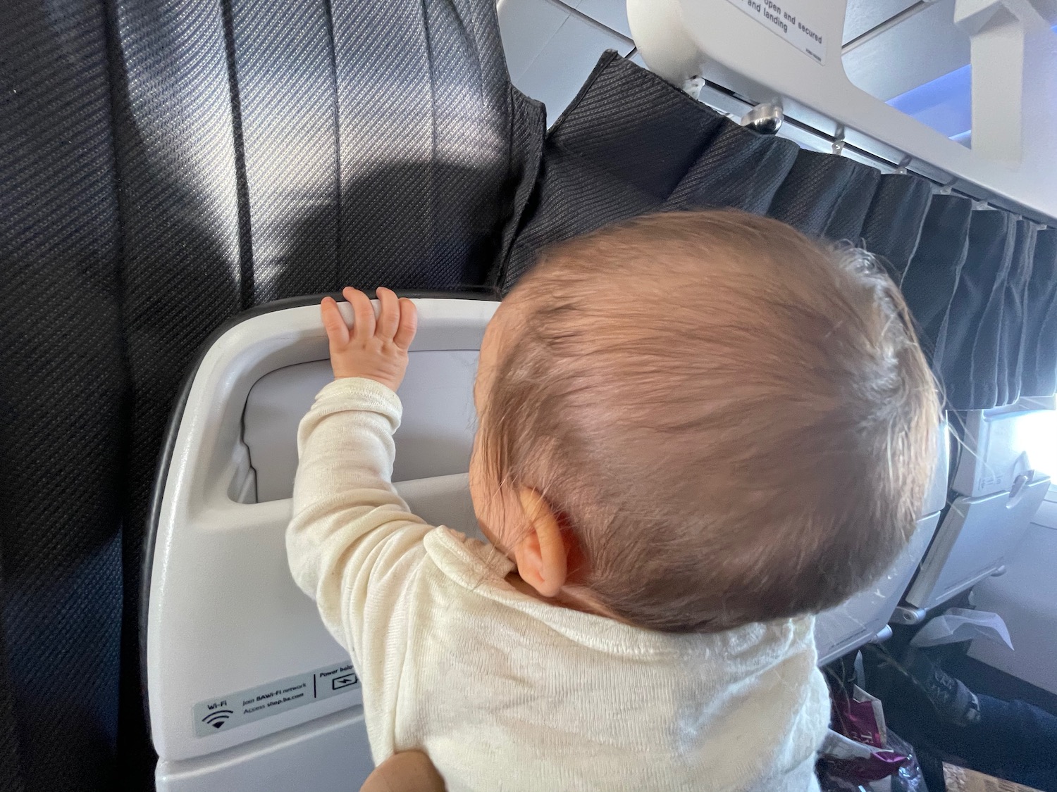 a baby reaching out to the side of a seat