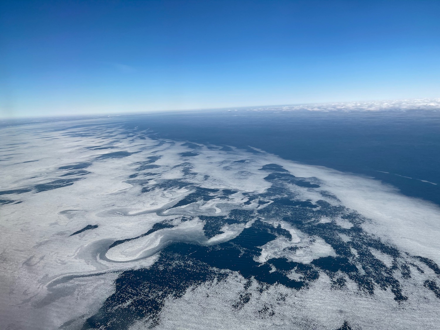 an aerial view of a body of water with ice and clouds