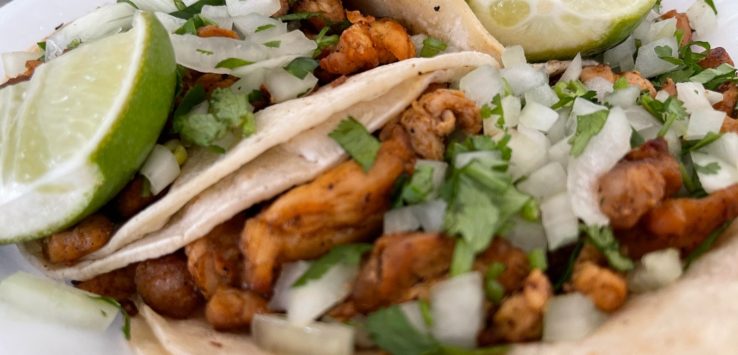 a plate of tacos with meat and limes