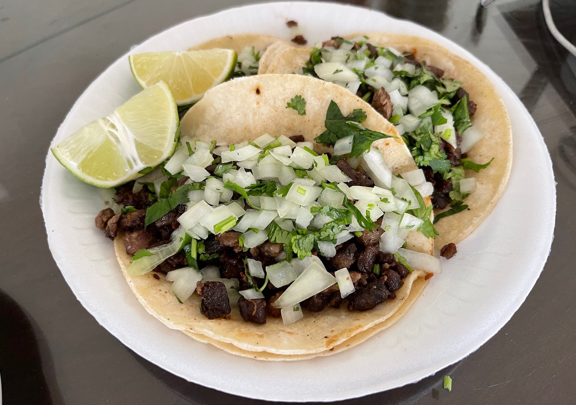 a plate of tacos with limes and onions