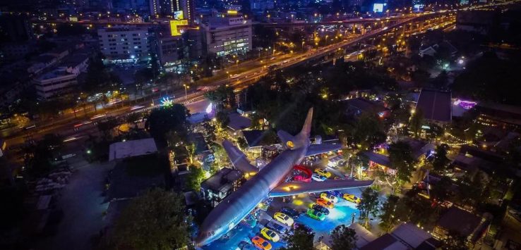 an airplane in a parking lot with cars and buildings in the background