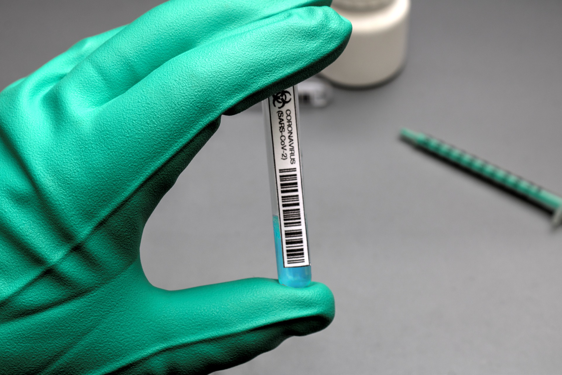 a hand in a glove holding a test tube