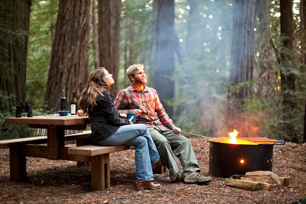 a man and woman sitting around a fire pit