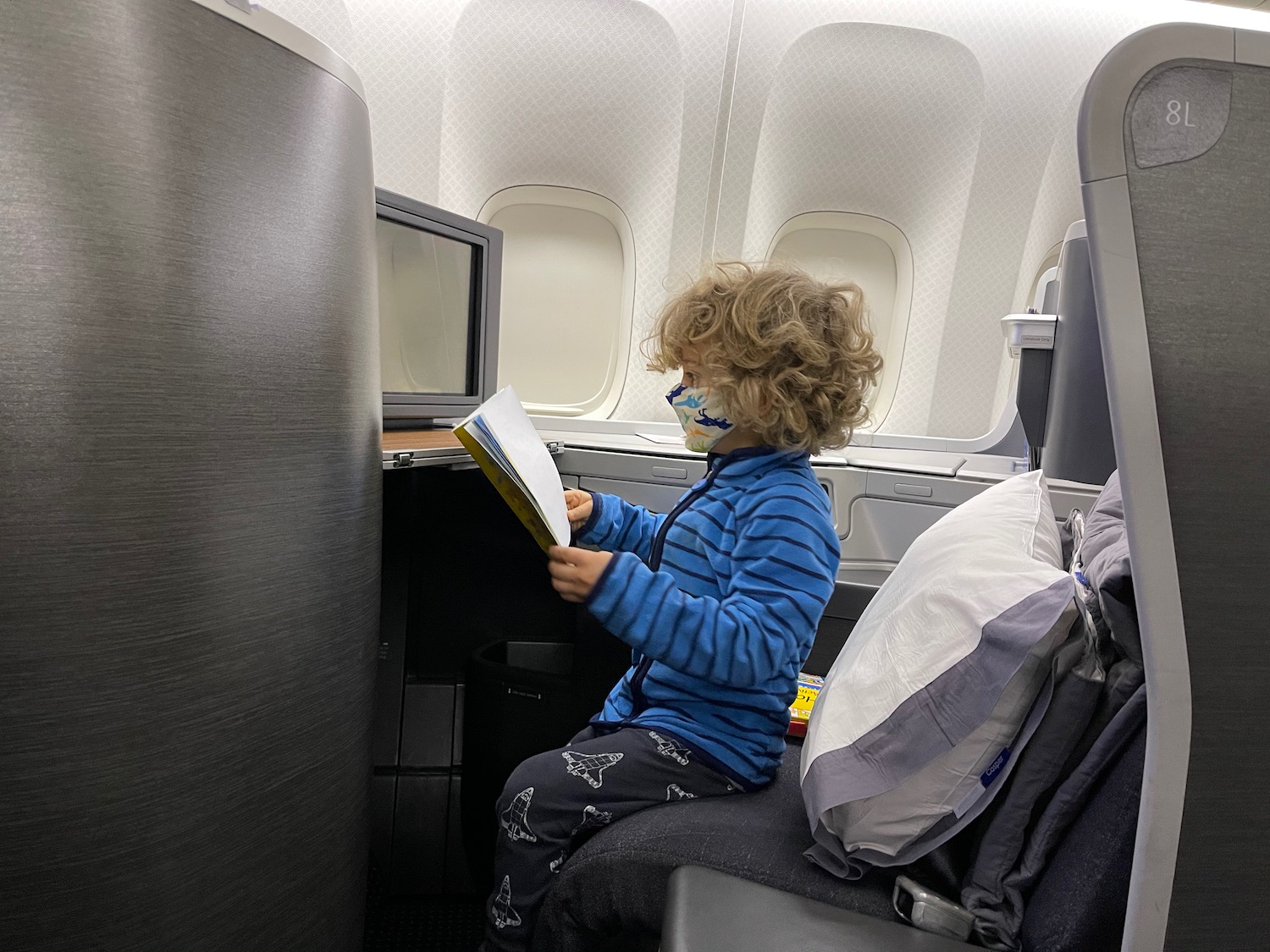 a child sitting on an airplane reading a book