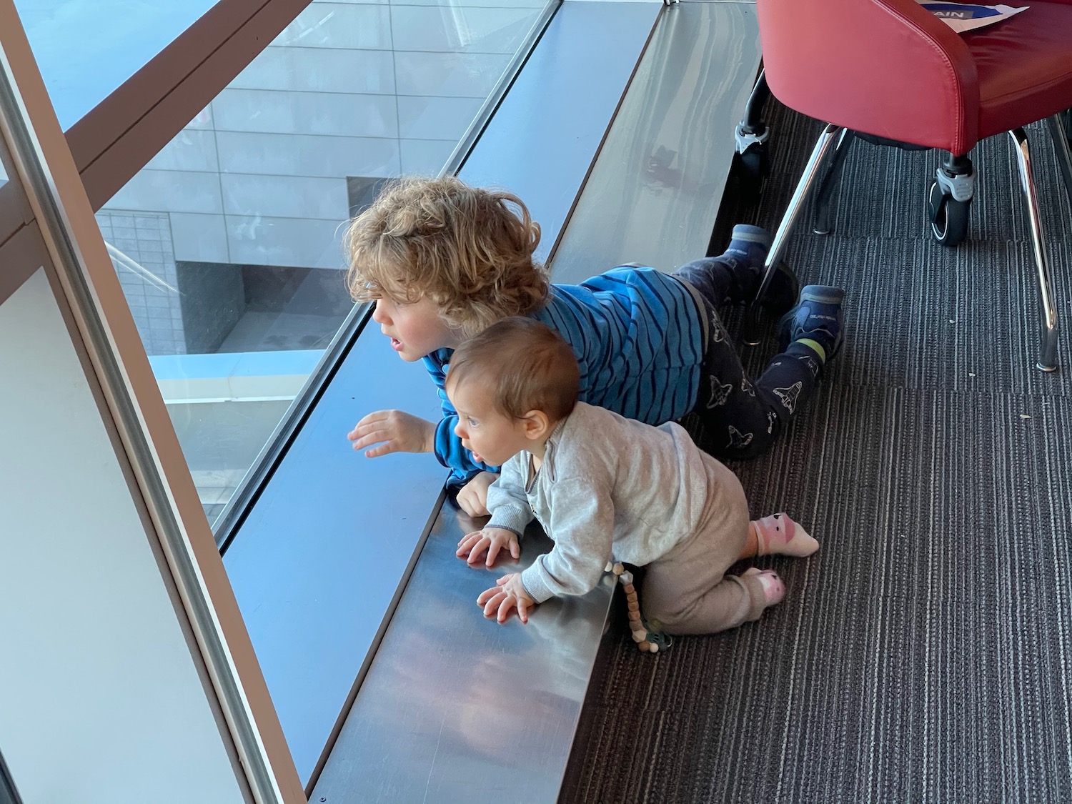 a boy and a baby looking out a window