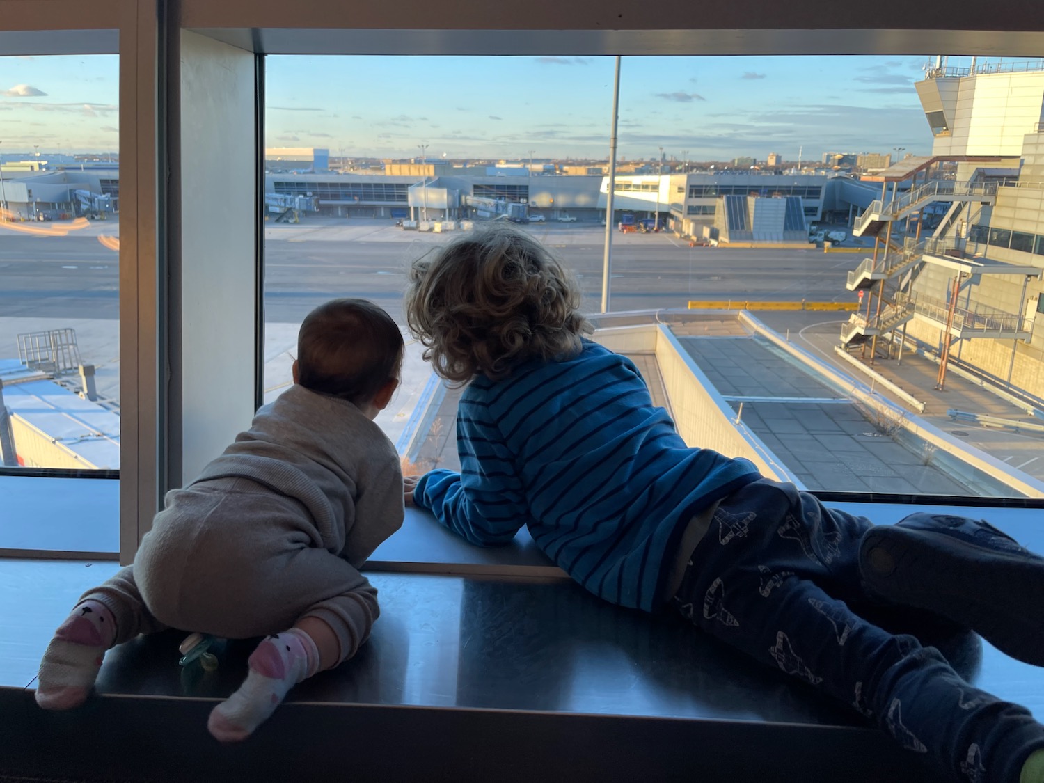 two children looking out a window at an airport