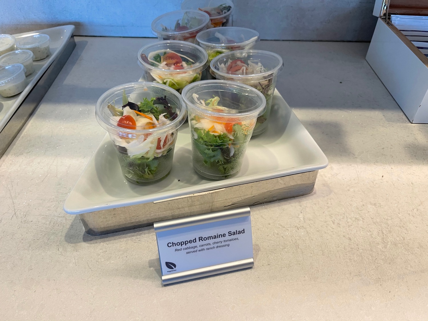 a group of plastic cups of salad on a white plate