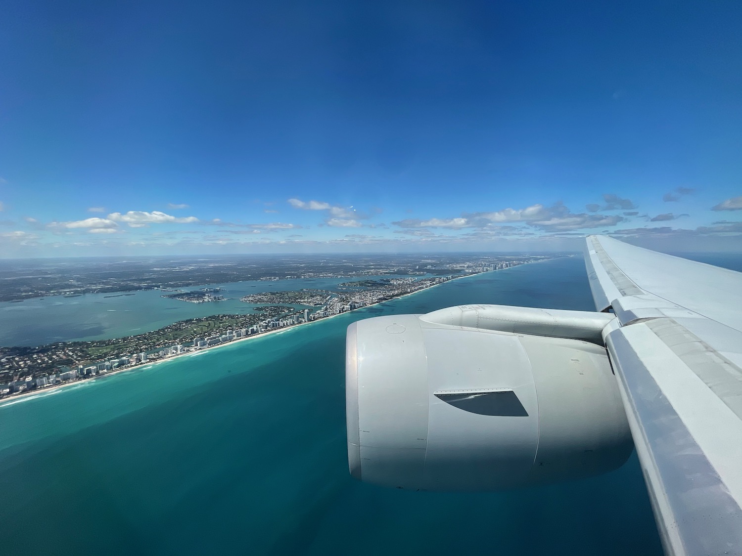 an airplane wing and water with a city in the background