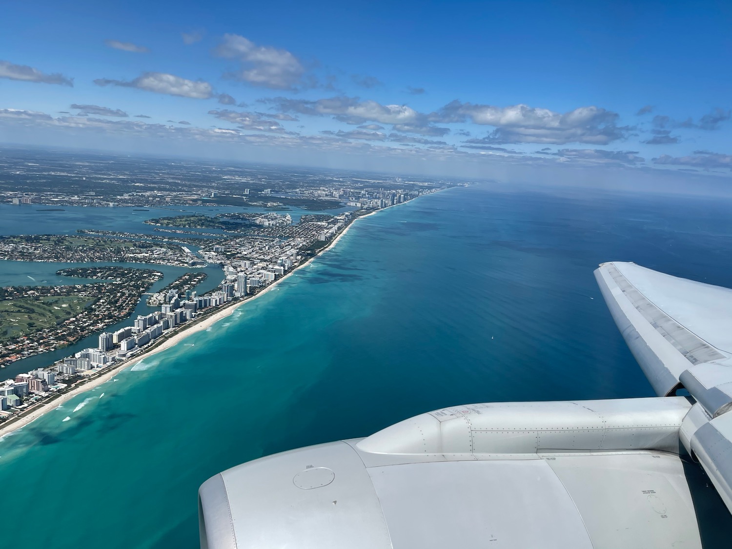 an airplane wing and a body of water with buildings and a beach