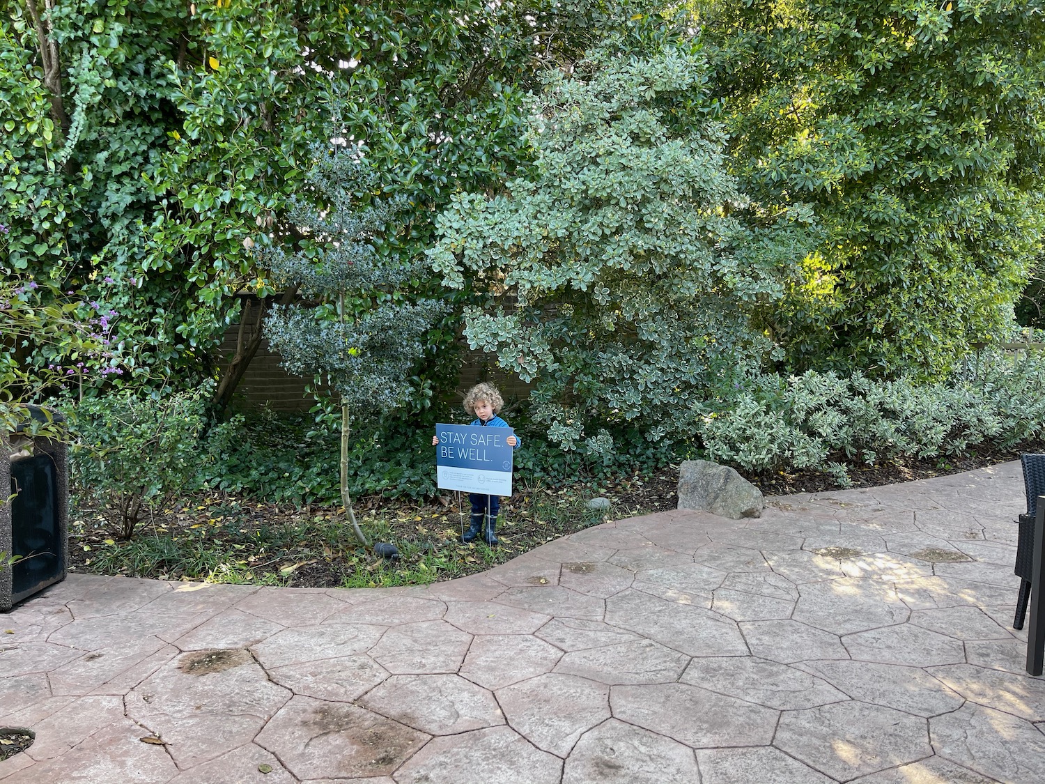 a child standing in a garden with a sign