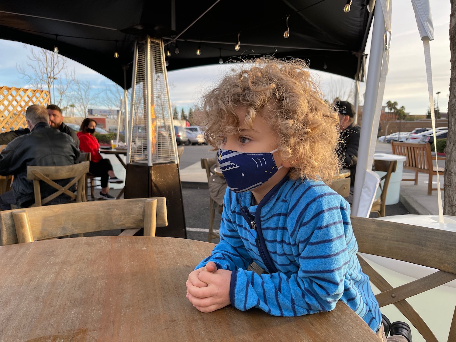 a child wearing a face mask sitting at a table