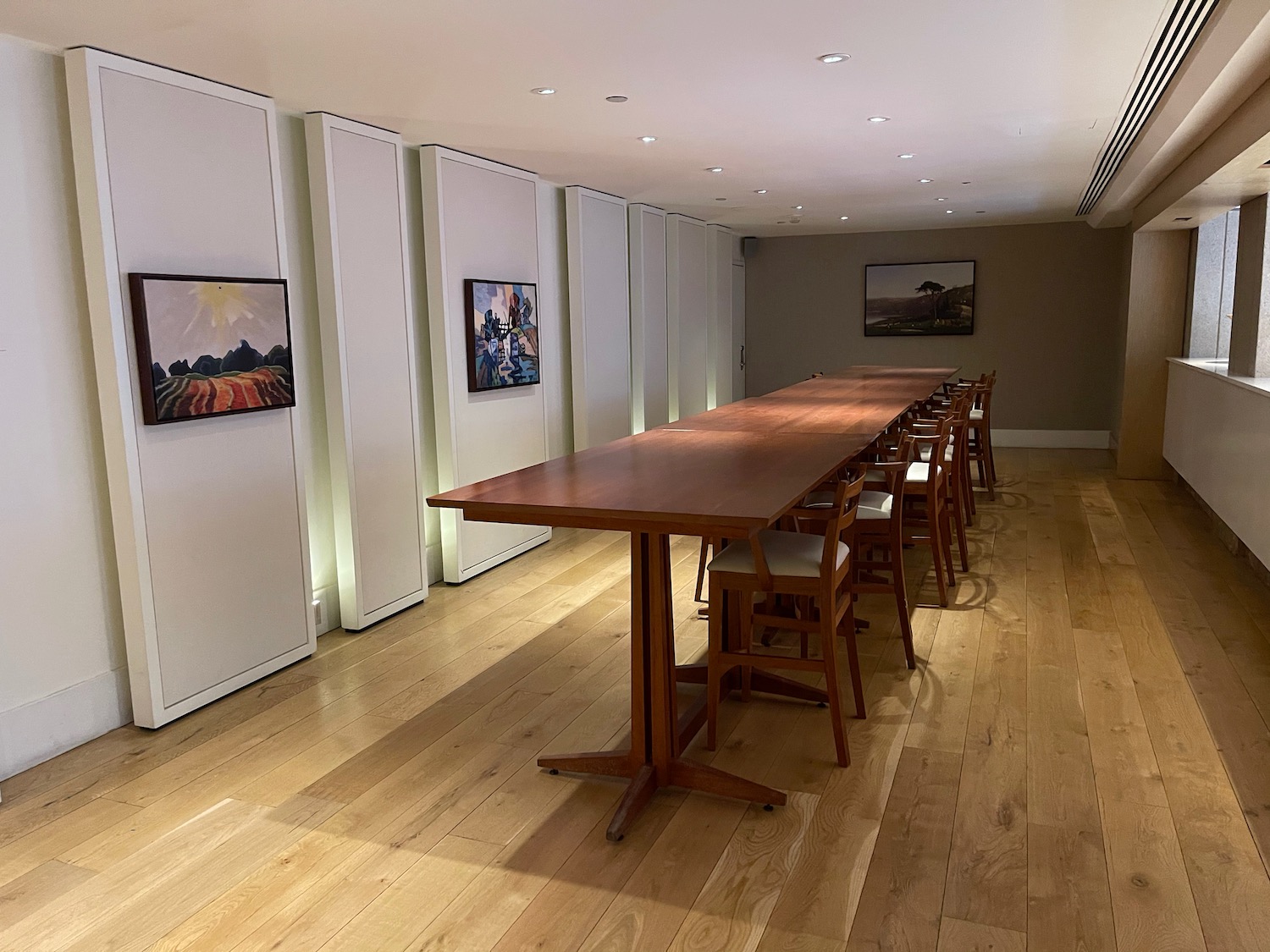 a long table with chairs in a room with art on the wall