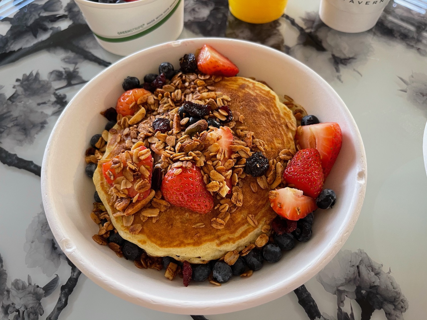 a bowl of pancakes with berries and granola