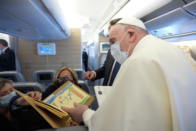 a man in a white robe and a mask reading a book on an airplane