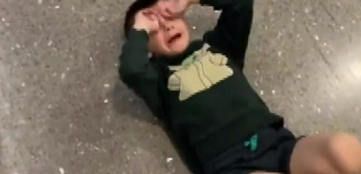 a boy lying on the ground with his hands on his face