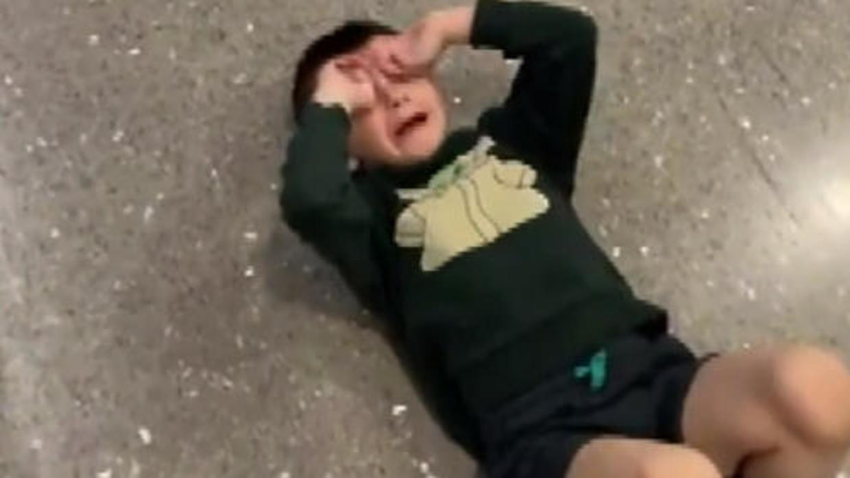 a boy lying on the ground with his hands on his face