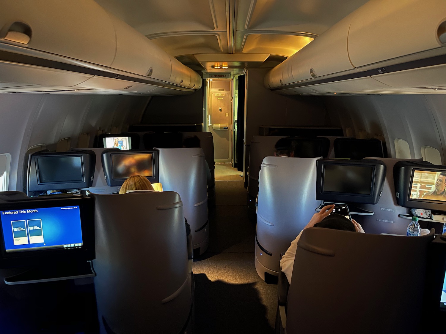 people sitting in an airplane with a few monitors