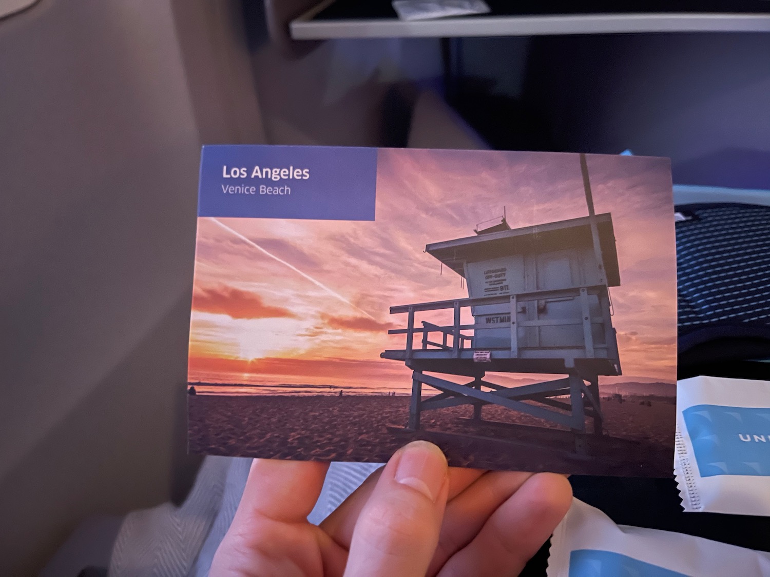 a hand holding a card with a beach and a sunset