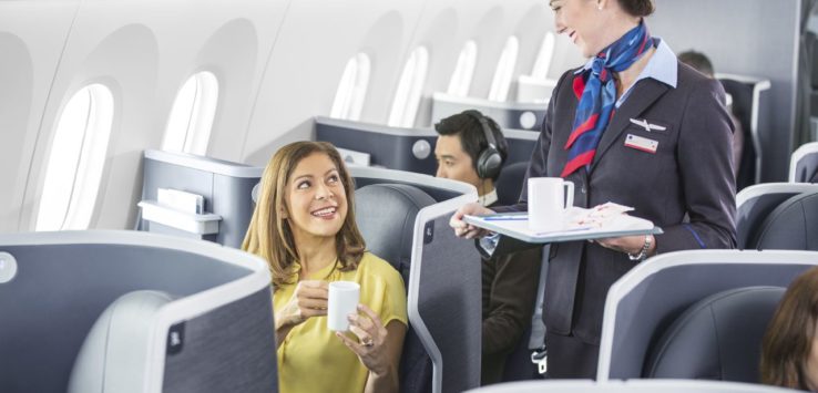 a flight attendant serving a woman to a couple of people