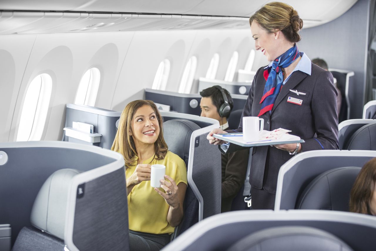 a flight attendant serving a woman to a couple of people