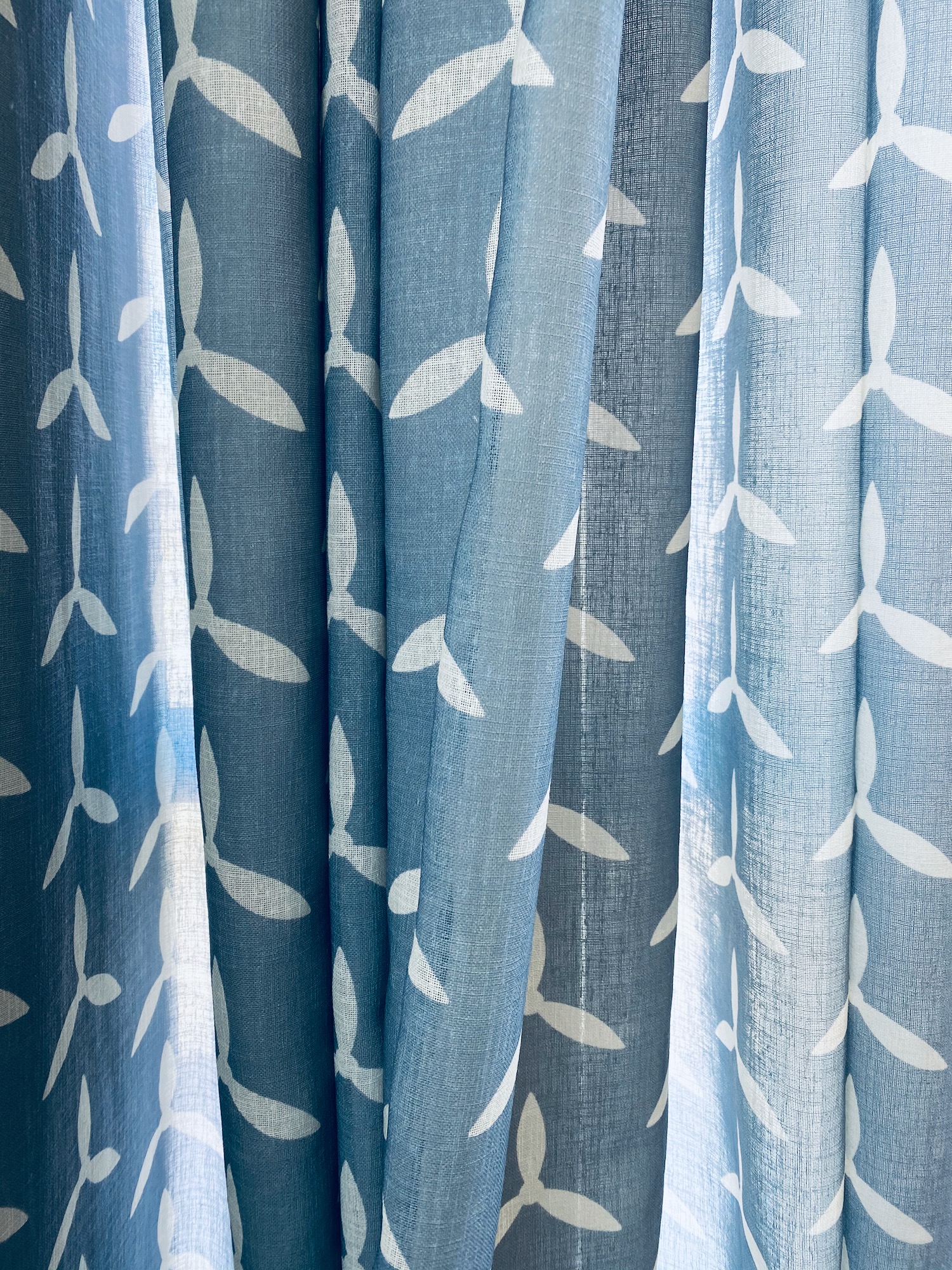 a blue and white curtain with white leaves on it