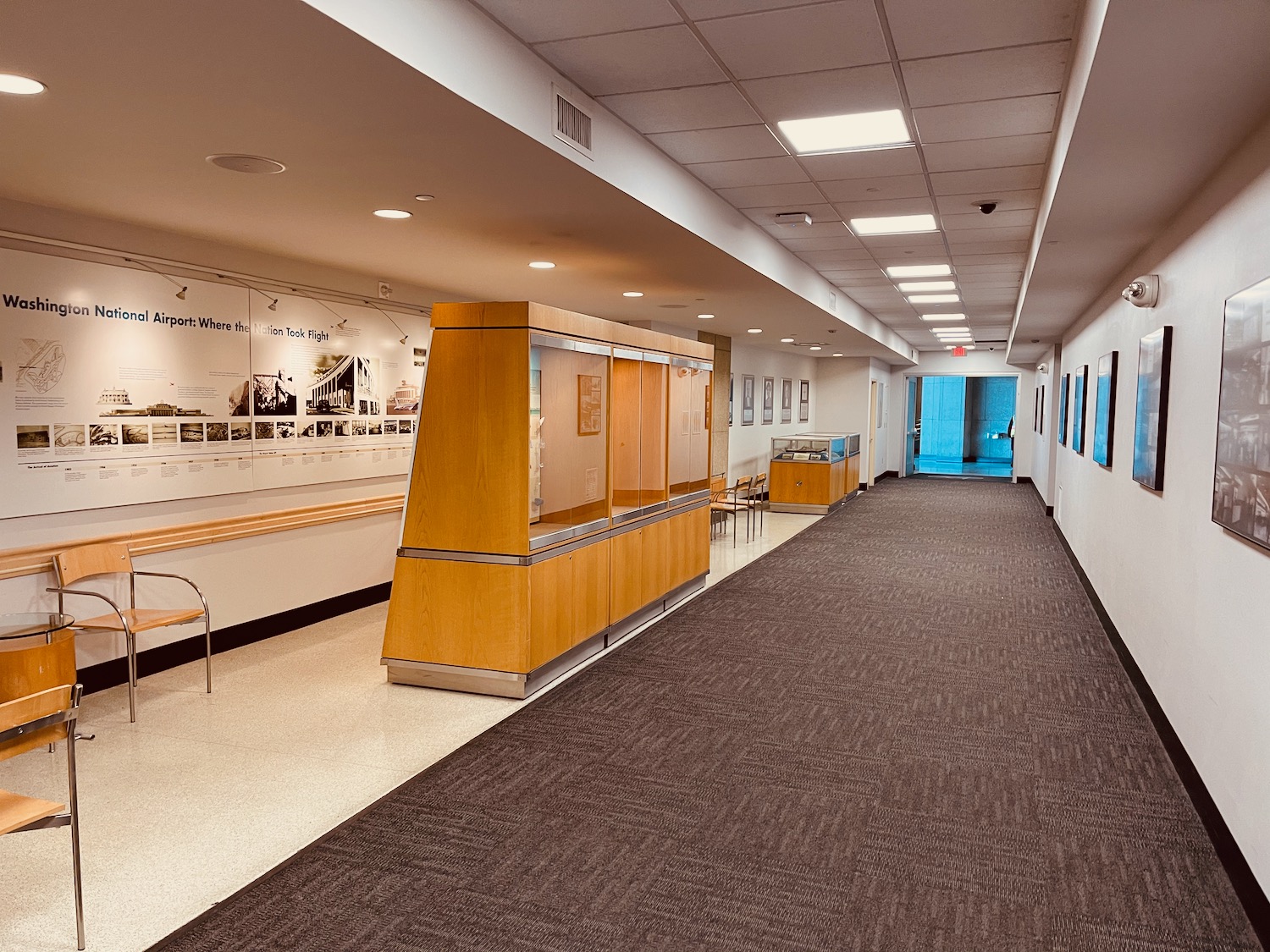 a hallway with a chair and a display case