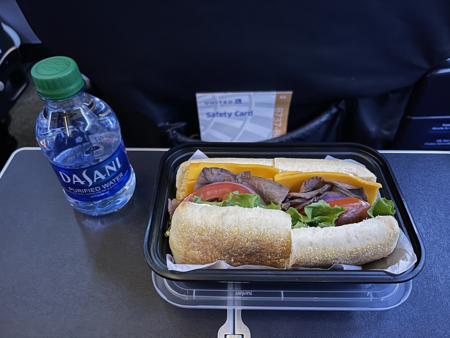 a sandwich in a container next to a bottle of water