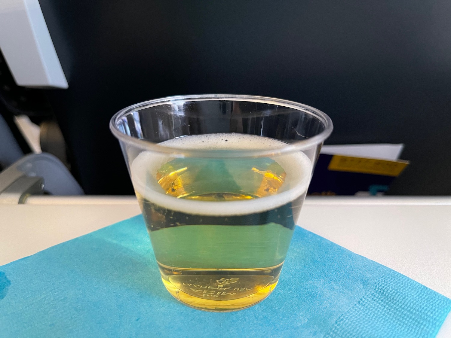 a clear plastic cup with yellow liquid on a blue napkin