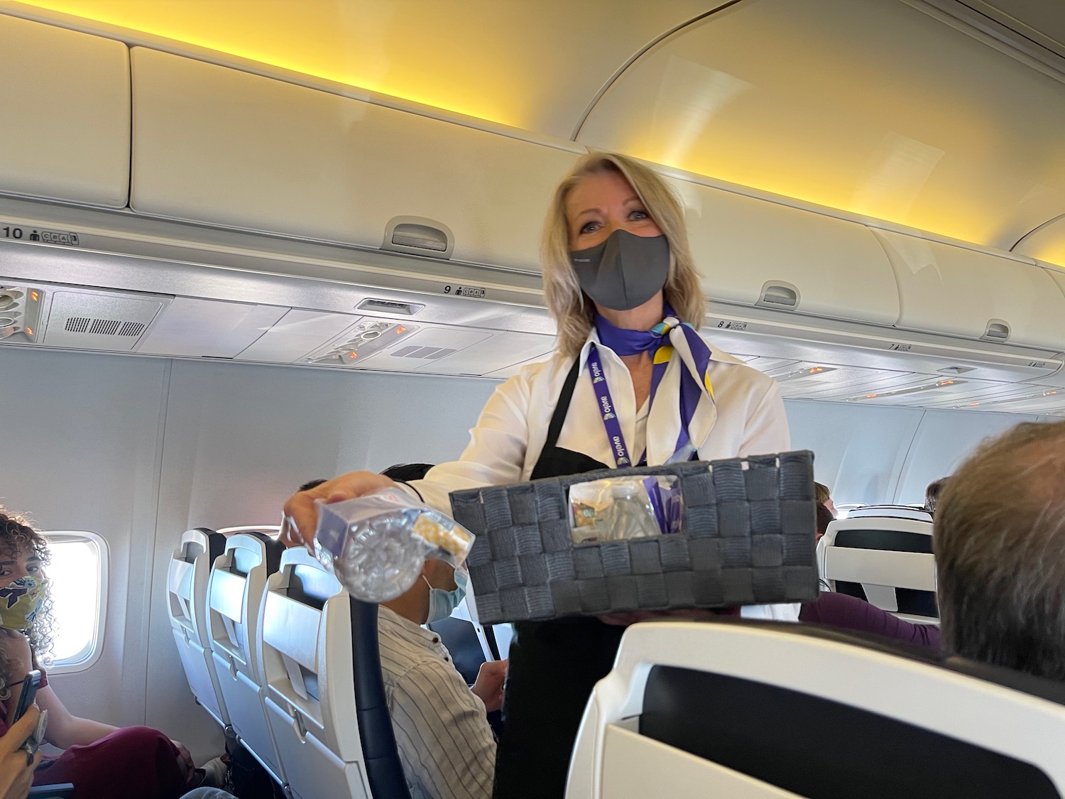 a woman wearing a face mask and holding a basket in an airplane