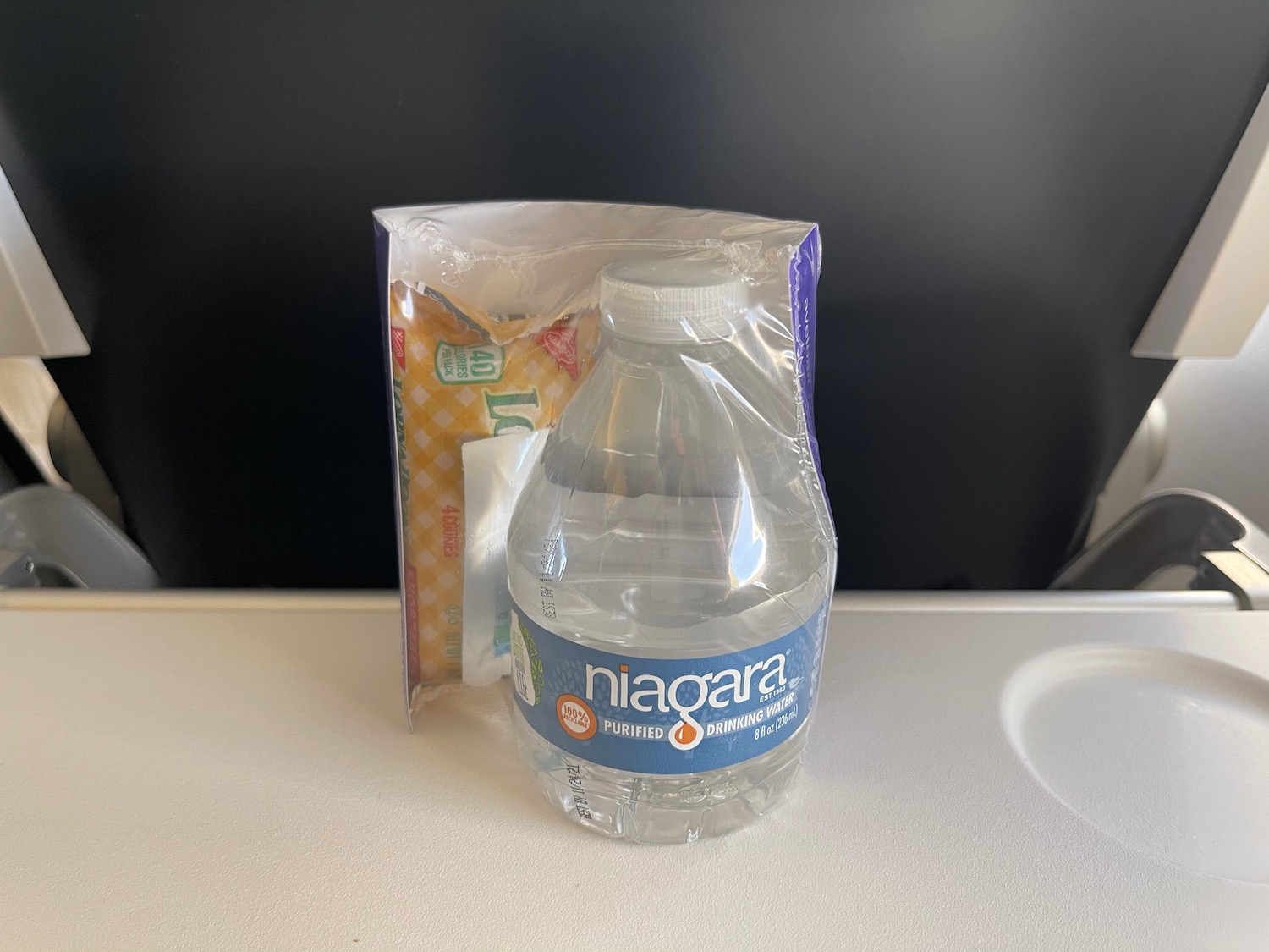 a plastic bottle of water next to a bag of chips