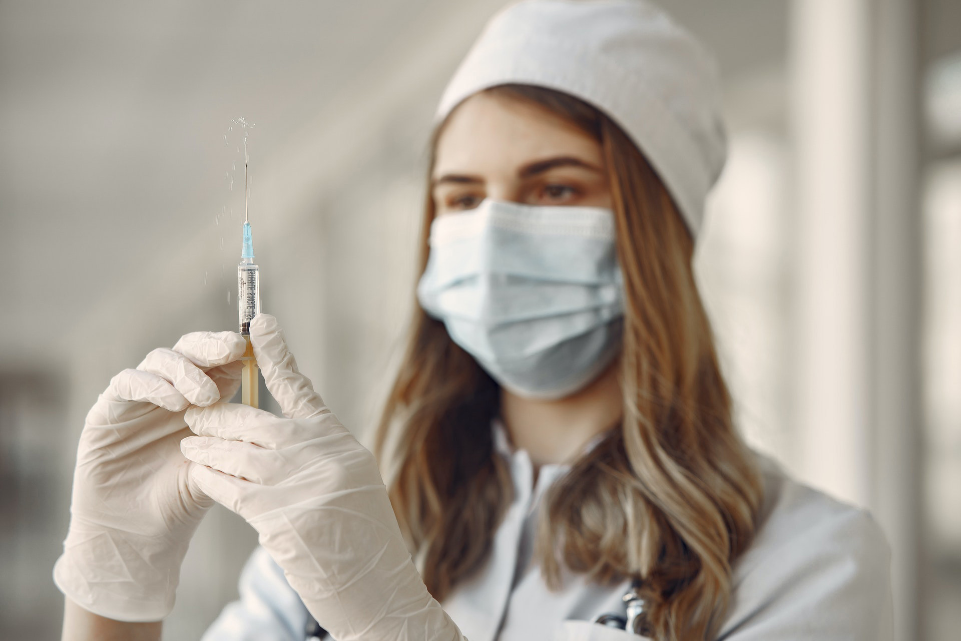 a woman wearing a mask and gloves holding a syringe
