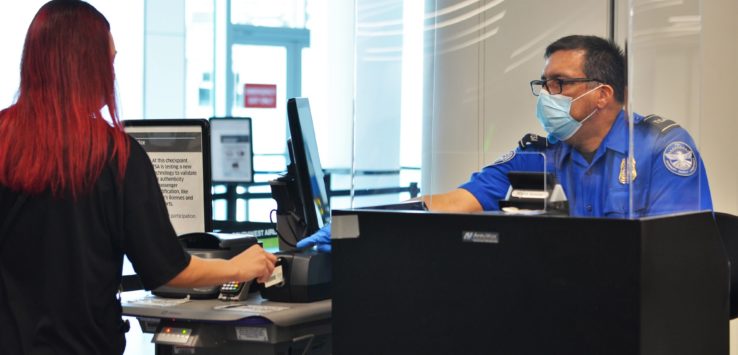 a man wearing a mask and a face mask at a check-in counter