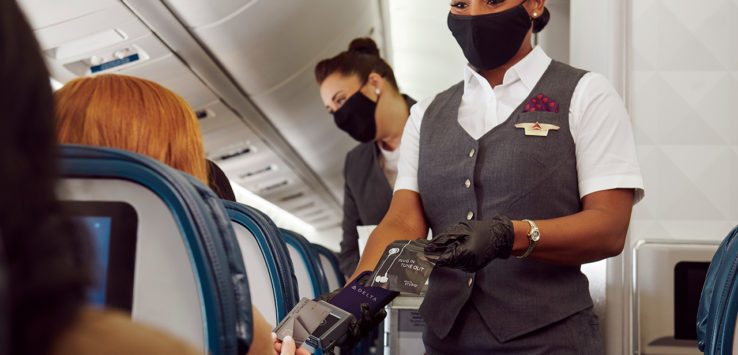 a woman wearing a mask and gloves handing a passport to another woman