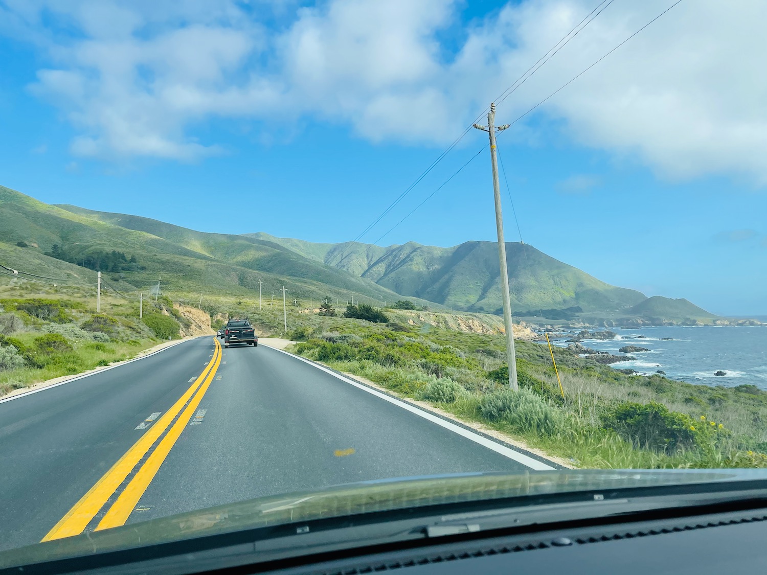 a car driving on a road with mountains in the background