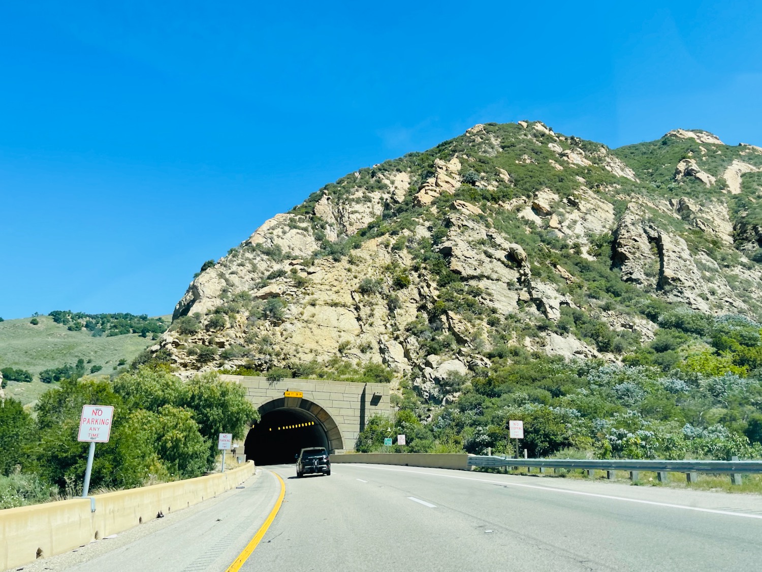 a car driving on a road with a tunnel